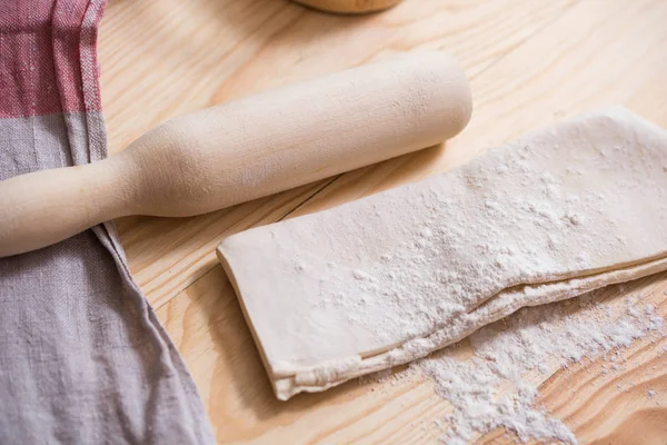 Preparation of the dough. Ingredients for the dough - Eggs and flour with a rolling pin. On wooden background.