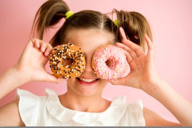 İki pembe donuts pembe, mor arka plan seyir genç kız portresi,