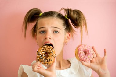 İki pembe donuts pembe, mor arka plan seyir genç kız portresi,