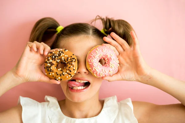 İki pembe donuts pembe, mor arka plan seyir genç kız portresi,