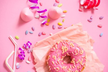 Parti. renkli şekerli yuvarlak camlı çörek pembe bir arka plan üzerinde. Kutlama kap, tinsel, şeker.