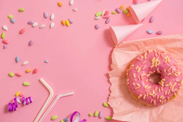 A party for girls. pink donut on crumpled paper, colorful candy. Top view, copy space. flat lay