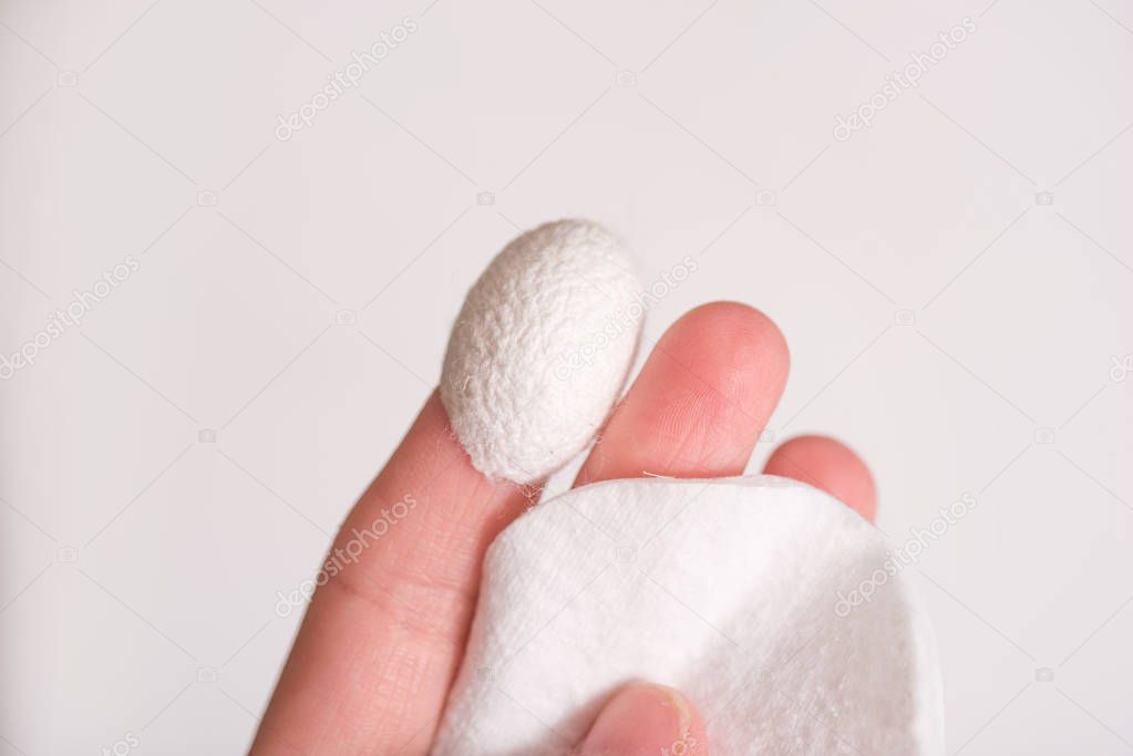 silkworm cocoon on finger with medical cream, cosmetology and skin procedures. Beauty salon and spa concept.