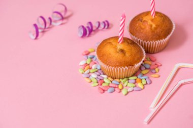 İki çikolatalı kek, Doğum günü mumu. Parti kızlar için. Kapaklar ve tinsel ve pembe bir arka plan kopya alanı üzerinde çok renkli tatlılar