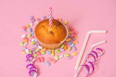 İki çikolatalı kek, Doğum günü mumu. Parti kızlar için. Kapaklar ve tinsel ve pembe bir arka plan üzerinde çok renkli tatlılar