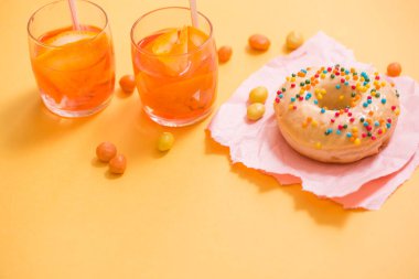 Çörek sprinkles ile sarı arka plan üzerinde tutan el.