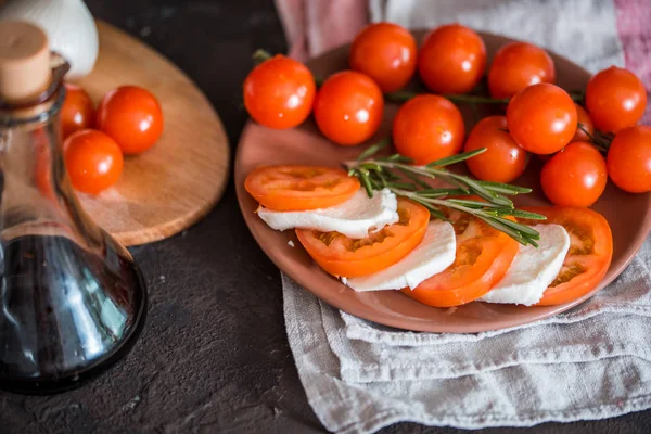 Italian bruschetta with chopped tomatoes, basil, mozzarella cheese and balsamic vinegar. Fresh homemade caprese bruschetta or crostini and ingredients on black background, copy space. — Stock Photo, Image