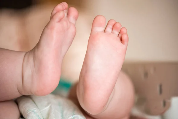脚三月的婴儿 浮肿的高跟鞋 他躺着 抬起双腿 — 图库照片