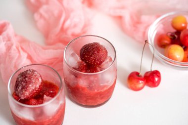 İki bardak vişne kompostosu, kiraz bir plaka üzerinde peçete pembe ahşap arka plan üzerinde. Seçici odak.