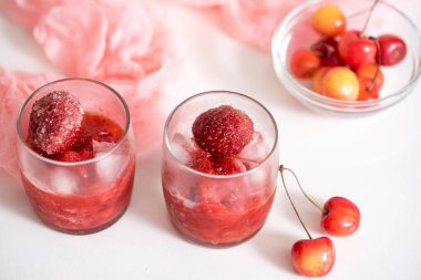 İki bardak vişne kompostosu, kiraz bir plaka üzerinde peçete pembe ahşap arka plan üzerinde. Seçici odak.