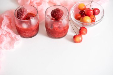 İki bardak vişne kompostosu, kiraz bir plaka üzerinde peçete pembe ahşap arka plan üzerinde. Seçici odak.