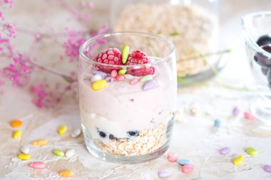 Yoğurt, müsli ve taze meyve salatası bir cam kase ahşap bir masa üzerinde detayları ile açık görünüm,