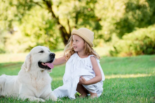 Sevimli sarışın kız ile bir yaz güneşli parkta beyaz büyük rottweiler köpek mavi gözlü. Dostluk kavramı