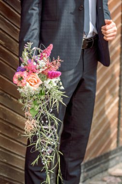 Yaratıcı düğün buket damat elinde. Sanat floristik. Koyu takım elbise.