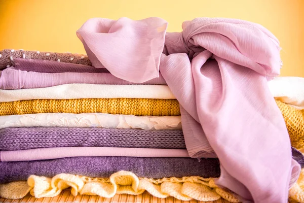 Pile of clothes on table. yellow purple purple and pink. Knitted jacket silk scarf. texture, copy spase