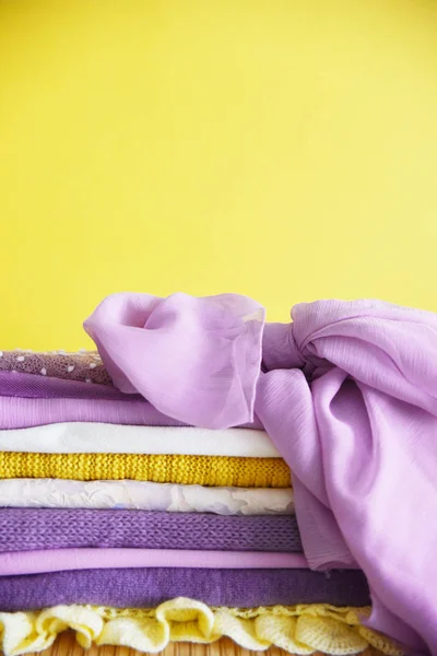 Pile of clothes on table. yellow purple purple and pink. Knitted jacket silk scarf. texture, copy spase