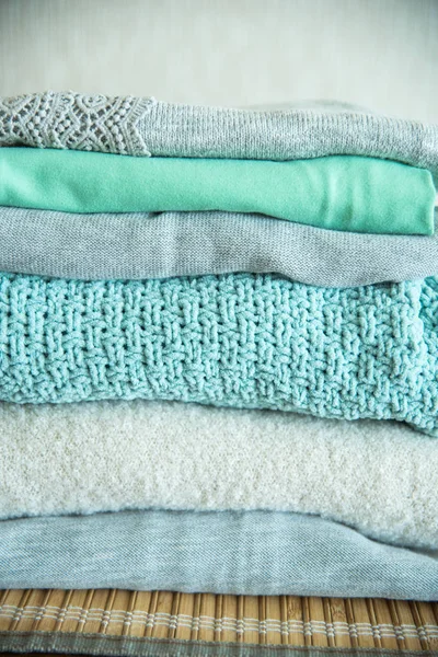 Pile of clothes on table. Turquoise and blue shirts and a knitted sweater