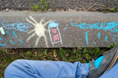 çocuk çizimleri kaldırıma boya kalemi ile. Bir ev, bir güneş, bulutlar ve yaz yağmuru. Çocukluk ve mutluluk kavramı.