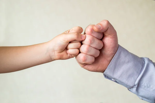 A big fist fights with a small fist. competition and victory, a fist of a child and an adult male close-up. Leader and winner