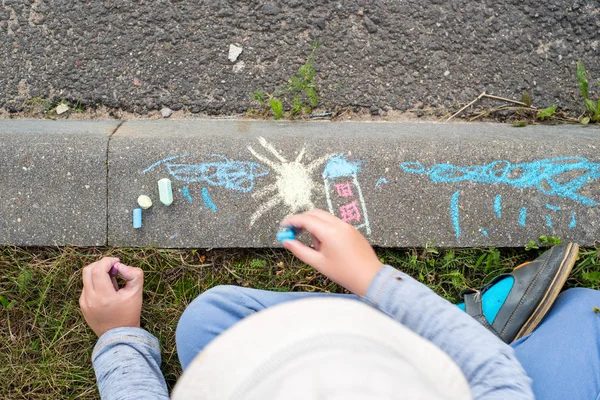 children\'s drawings with crayons on the pavement. A house, a sun, clouds and a summer rain. The concept of childhood and happiness.