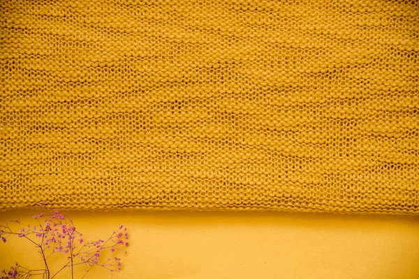 knitted texture. yellow clothes and purple dried flowers. autumn concept