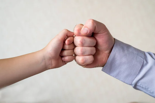 A big fist fights with a small fist. competition and victory, a fist of a child and an adult male close-up. Leader and winner