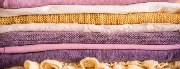 Uzun banner. Tablo üzerinde elbise yığını. sarı mor mor ve pembe. Örme ceket ipek eşarp