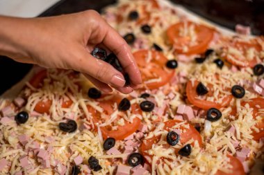 Siyah önlük Şef pizza pizza için malzemeler masanın üzerine koyarak elleri ile yapar.