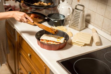 Kadın mutfakta et lazanya hazırlanıyor. et, domates ve peynir ile onun elini