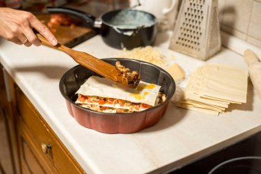 Kadın mutfakta et lazanya hazırlanıyor. et, domates ve peynir ile onun elini