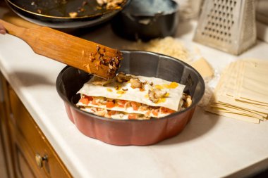 Kadın mutfakta et lazanya hazırlanıyor. et, domates ve peynir ile onun elini