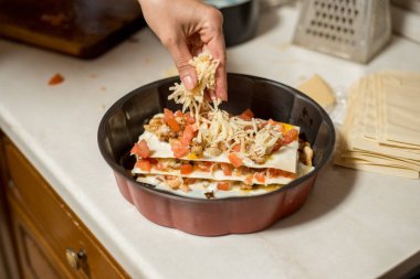 Kadın mutfakta et lazanya hazırlanıyor. et, domates ve peynir ile onun elini