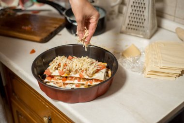 Kadın mutfakta et lazanya hazırlanıyor. et, domates ve peynir ile onun elini