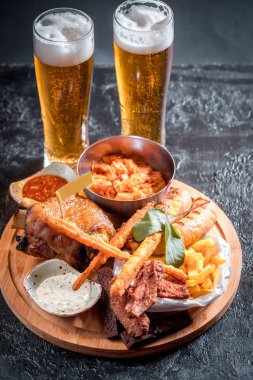 Köpüklü bira bir cam, sıcak meze, tavuk kanadı kase içinde güzel bir sos. Catrofel ve diğer sebze kızartılmış. sağlıksız yiyecek. sağlıksız yiyecek. çok kalori