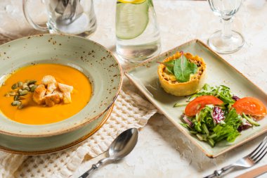 restoranda ayarlayın. Öğle Yemeği sonbahar menüsünde. kruton ve tohum ve sıcak patates püresi kabak çorbası et ile pişmiş. taze sebze salatası.