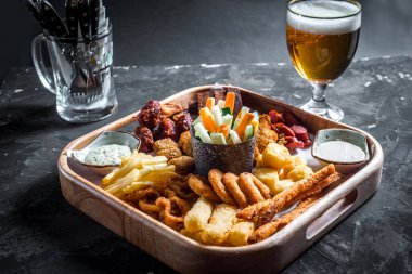 Çeşitli bira aperatifler - sosis, tavuk kanatları, kruton, soğan halkaları ve ahşap tahta sos ile kalamar halkaları ve oktoberfest Bira bardak seti