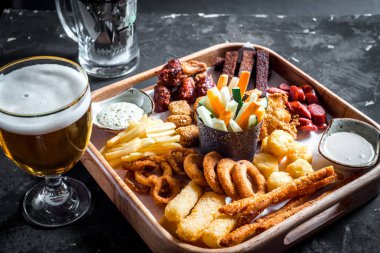 Çeşitli bira aperatifler - sosis, tavuk kanatları, kruton, soğan halkaları ve ahşap tahta sos ile kalamar halkaları ve oktoberfest Bira bardak seti