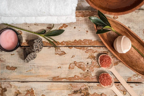 Kahverengi havlu ile spa ayarı ve çiçekler ile su kase görünümünü ahşap arka plan üzerinde top. Mum ışığı ayarda doğal spa ahşap masa üzerinde bir yüksek açı bakış. Metniniz için kopya alanı.