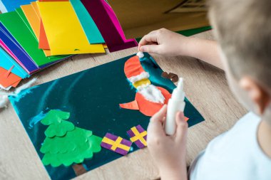 Çocuk bir Noel top dekor elinde tutuyor. Çocuk bir Noel top dekor gösteriyor. Basit el sanatları ve faaliyetleri çocuklar için geri dönüştürülmüş. Noel dekor ahşap bir masa ayarla