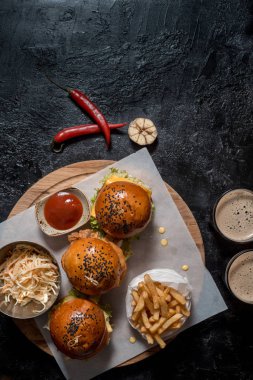 Üç hamburger, patates kızartması, ketçap sos, salata ve iki bardak koyu bira ayarlayın. İçten bir koyu arka plan en iyi görünümde Oktoberfest için ayarlamak. kopya alanı