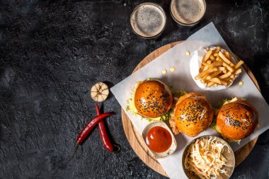 Üç hamburger, patates kızartması, ketçap sos, salata ve iki bardak koyu bira ayarlayın. İçten bir koyu arka plan en iyi görünümde Oktoberfest için ayarlamak. kopya alanı