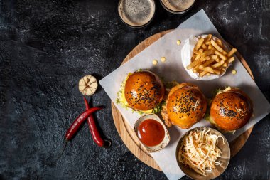 Üç hamburger, patates kızartması, ketçap sos, salata ve iki bardak koyu bira ayarlayın. İçten bir koyu arka plan en iyi görünümde Oktoberfest için ayarlamak. kopya alanı