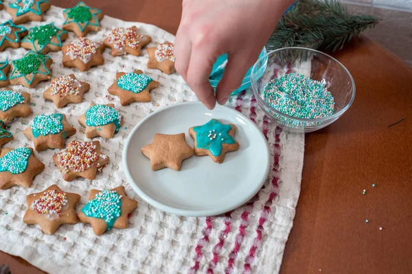 The process of baking and decorating Christmas gingerbread. hands mix turquoise glaze and paint gingerbread at home.