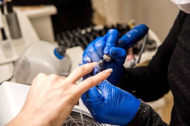 Tırnak teknoloji çivi törpü ile dosyalama. Profesyonel manikür araçları. Ustanın ellerinde mavi eldiven