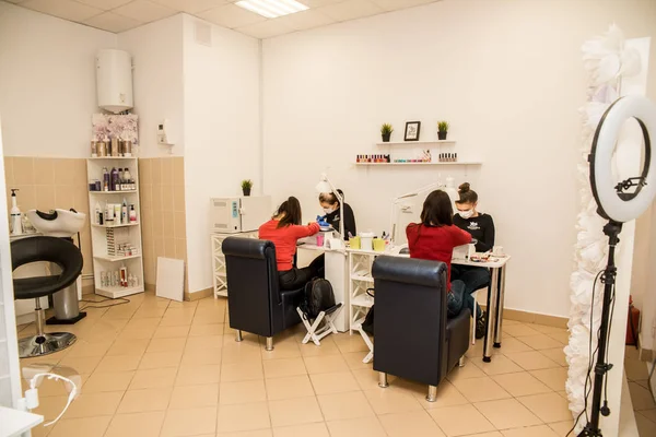 Offering color. Experienced nail artist wearing white shirt and bright gloves offering nice nail polish colors her client