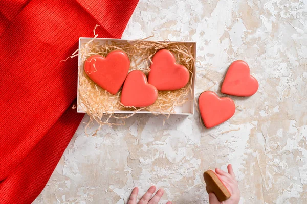 Homemade gingerbread with letters love for Valentine\'s Day on a background, Red icing, valentine hearts, top view. copy space. baby\'s hand, little baby