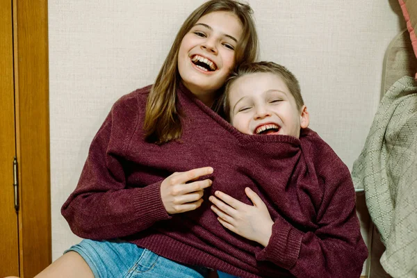 the kids are joking, one sweater for two, laughing and dabbling. Brother and sister are funny. Fool\'s day concept