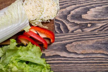 Taze yeşil marul, lahana, tatlı kırmızı biber ahşap arka plan üzerinde. Vejetaryen sebze salatası yemek pişirmek için. Diyet ve sağlıklı beslenme. kopya alanı