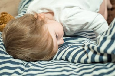 Yatakta uyuyan bebek bir oyuncak ayı tutarak. Yatmadan önce iskambil