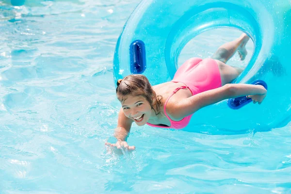 Funny girl taking a fast water ride on a float splashing water. Summer vacation with water park concept